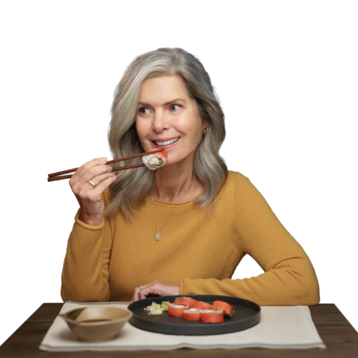 older woman enjoying sushi takeout at home